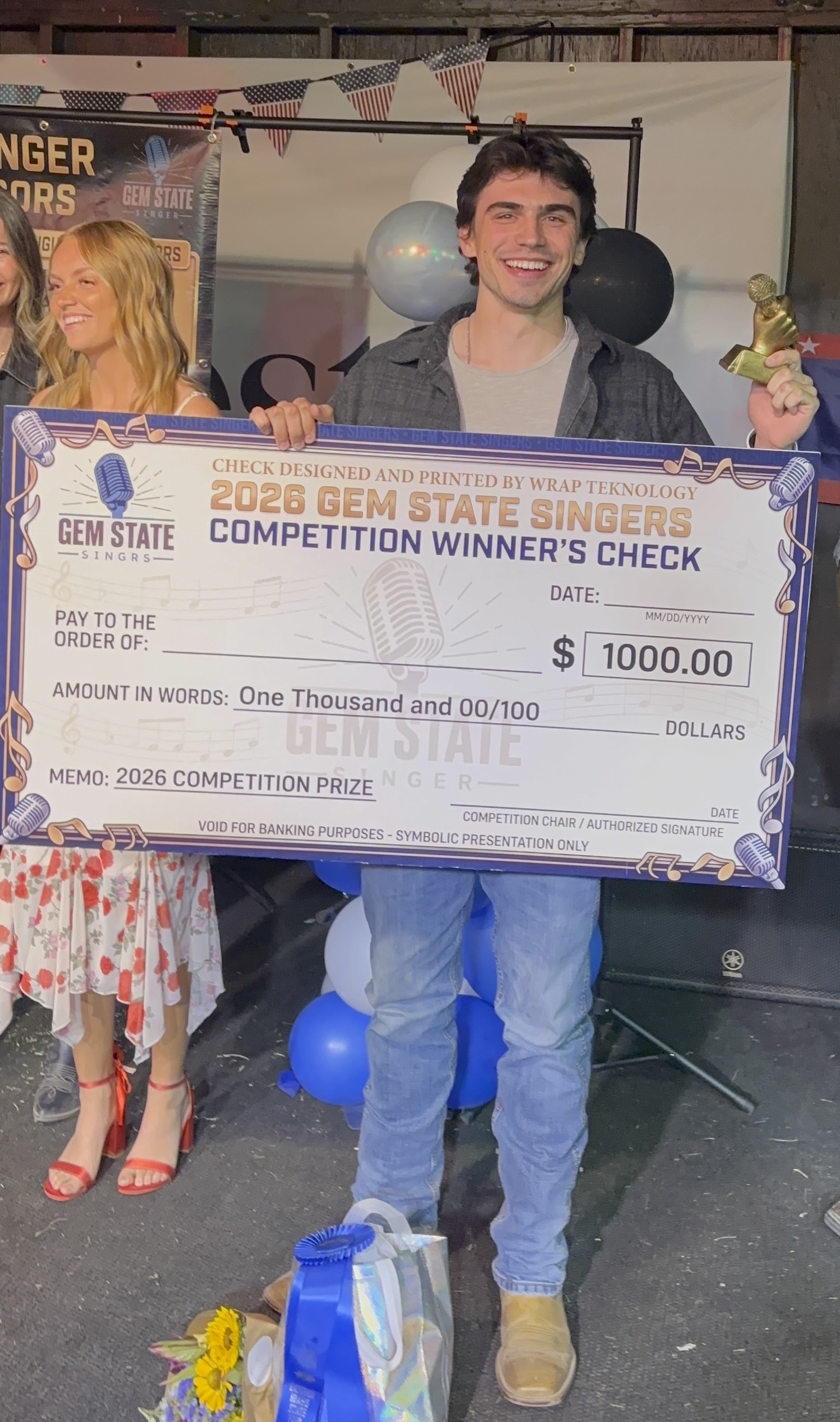 Pierce Nielsen holding the 2026 Gem State Singer winner's check